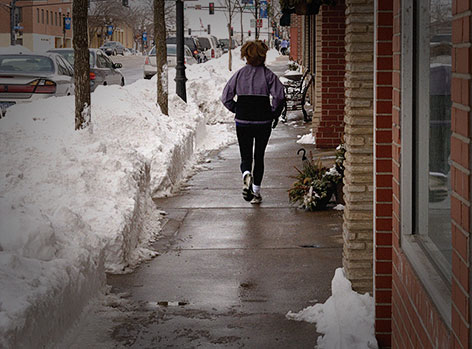 Woman running on snowy sidewalk